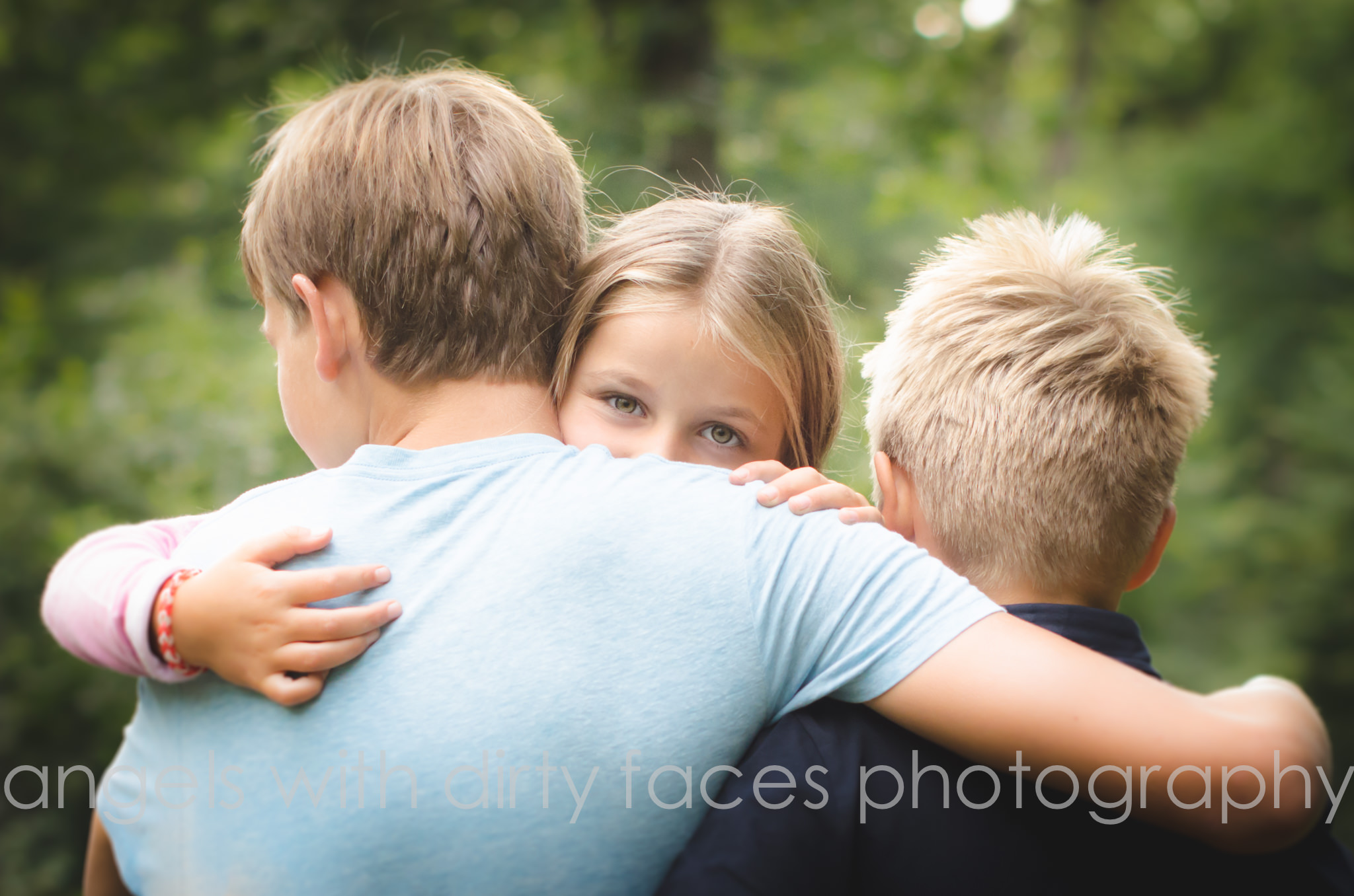 three siblings hug on their woodland family photo shoot