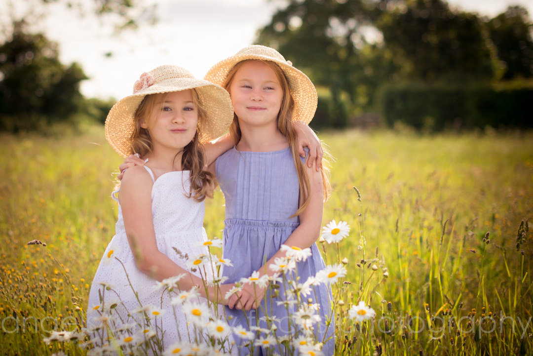 family photographer in welwyn garden city captures smiling sisters in field full of flowers