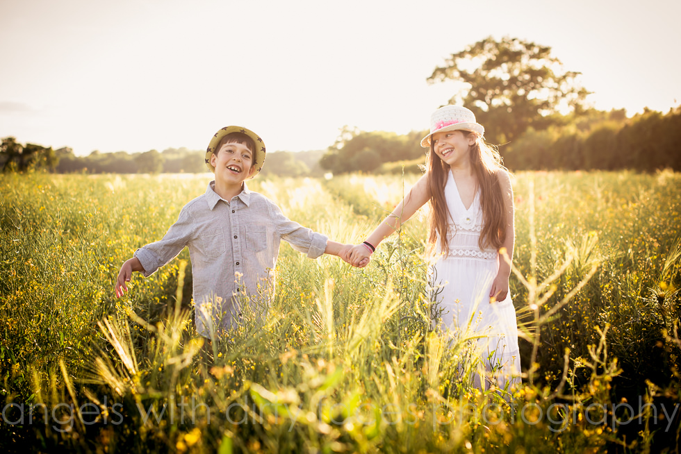 natural child photography in hertfordshire with siblings who are holding hands in the sunset