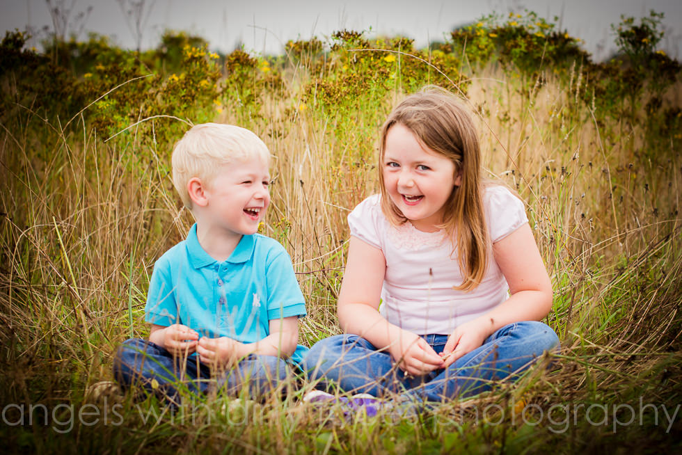 kids giggle in the long grass during their natural family photography shoot