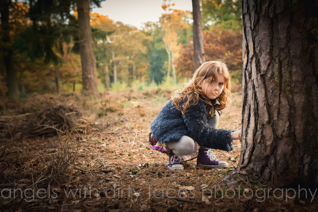 Young girl finds sticks by a tree during herNatural Family Photoshoot 
