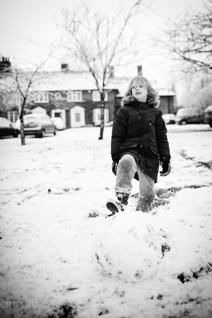 Child Lifestyle Photography in the snow with young boy making snowmen
