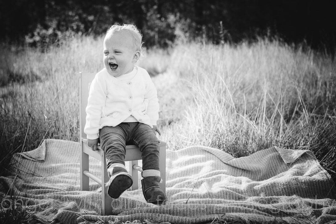 little girl laughs on a small chair during her Family Photo Shoot 