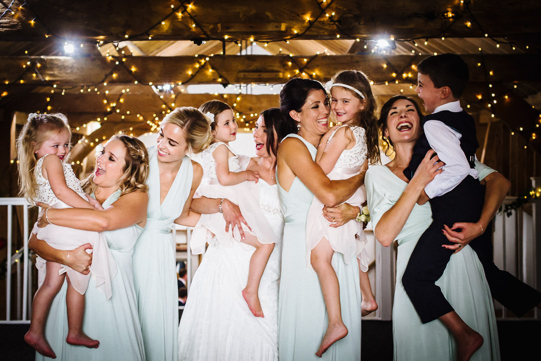 children at wedding are carried by bridesmaids for photography