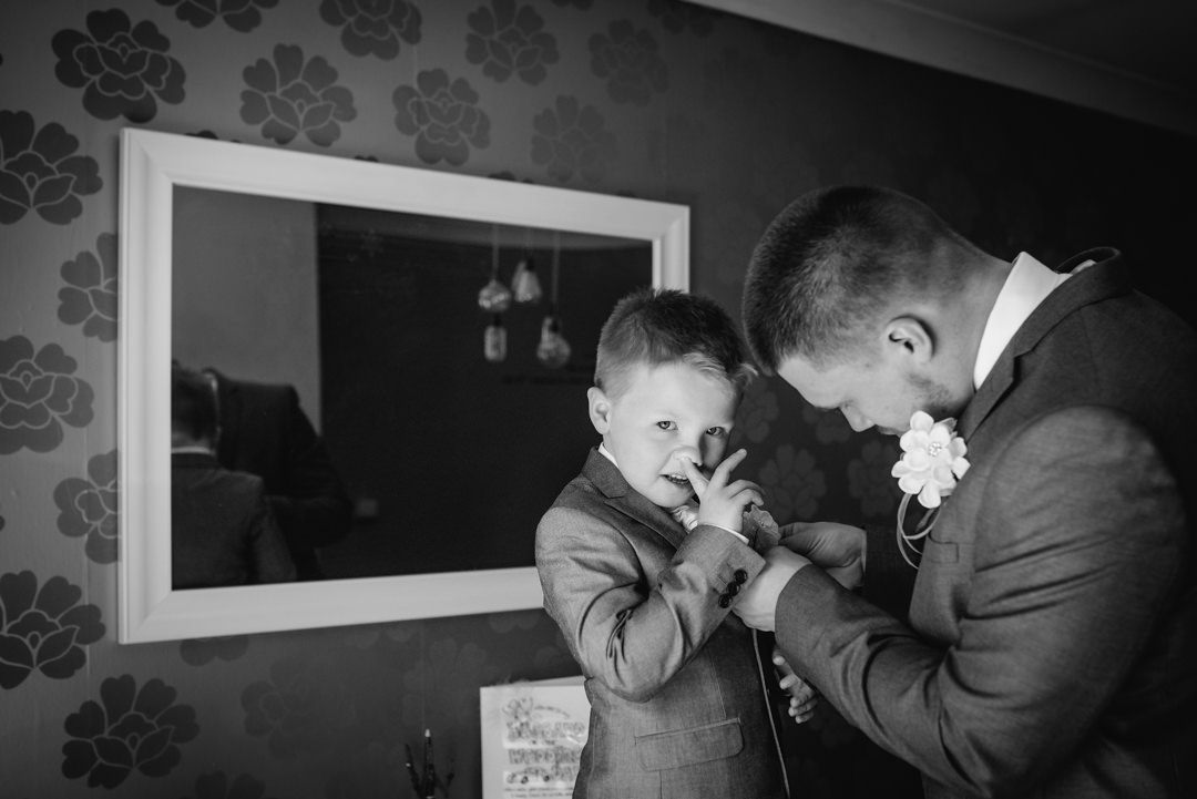 Little boys picks his nose whilst getting ready for Hertfordshire wedding photography