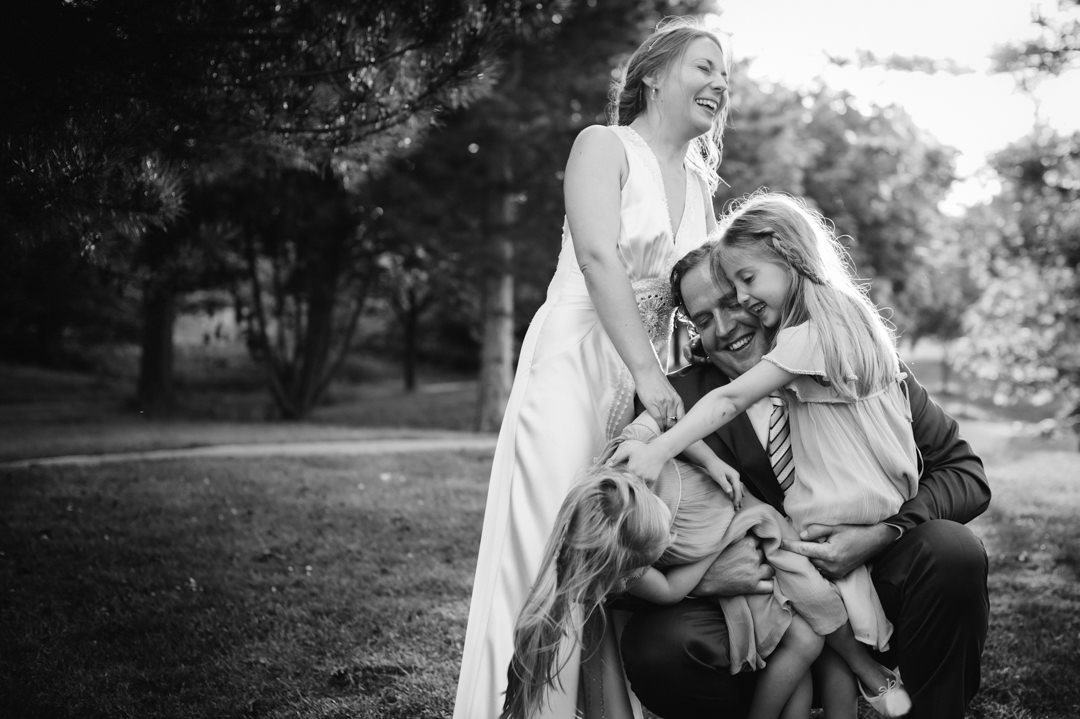 Bride and groom tickle their children after the wedding ceremony