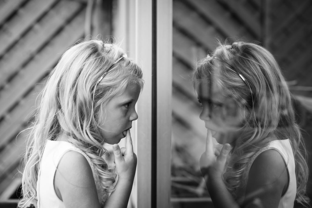 Little wedding guest pulls faces at her reflection in Hertfordshire wedding