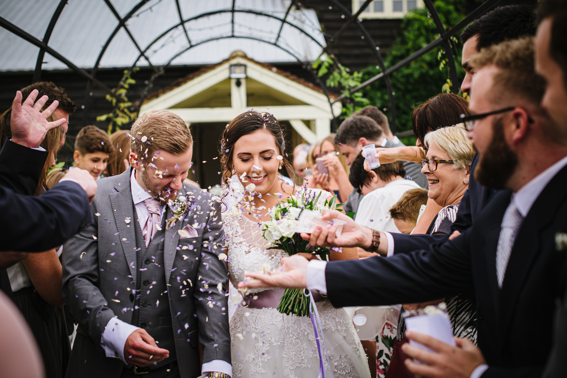 Guests throw confetti at the happy couple after their wedding ceremony at Milling Barn, Hertfordshire