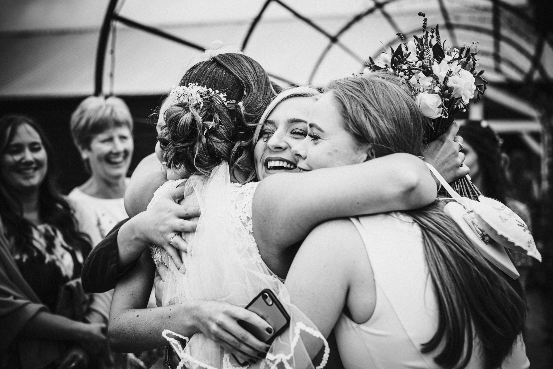 Bride and her friends cuddle after wedding ceremony