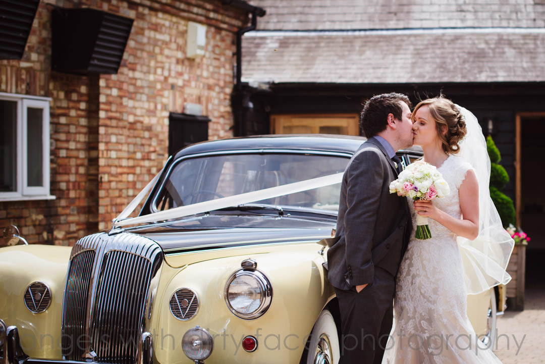 tewin bury farm  hotel wedding photography showing bride and groom kissing in front of car