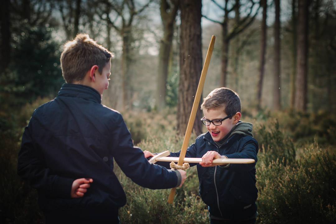 welwyn garden city family photographer playing sword fights with two boys in the woods