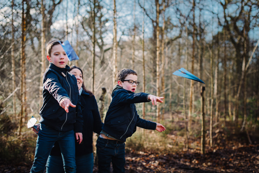 paper aeroplane throwing in the woods captured by welwyn garden city family photographer