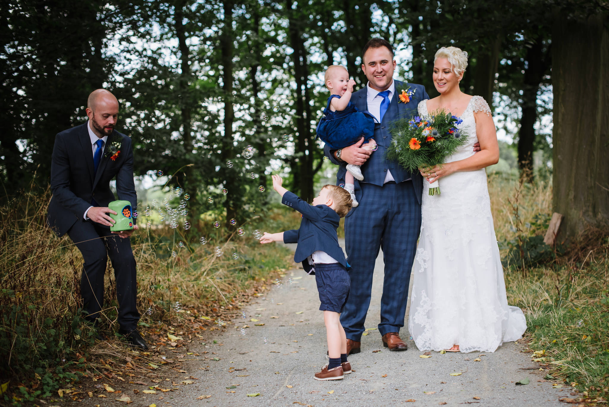 bride and groom play with their kids at their alwickbury park wedding