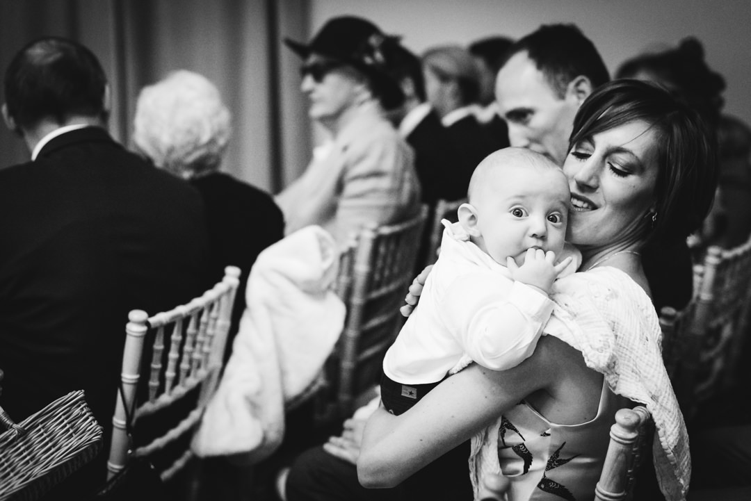 baby looks straight into the camera whilst waiting for the bride and groom