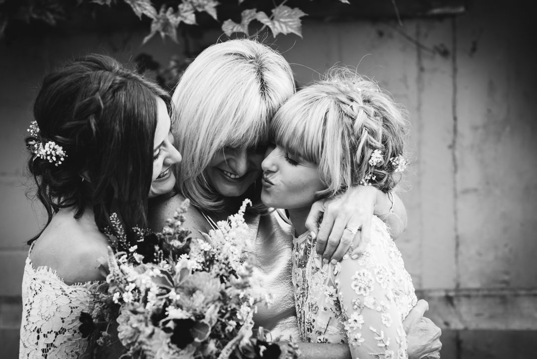 mother of the bride kisses her two daughters at houchins farm