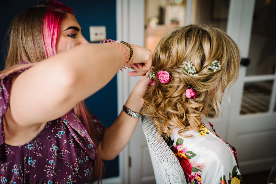 pink flowers being styled into a brides hair 