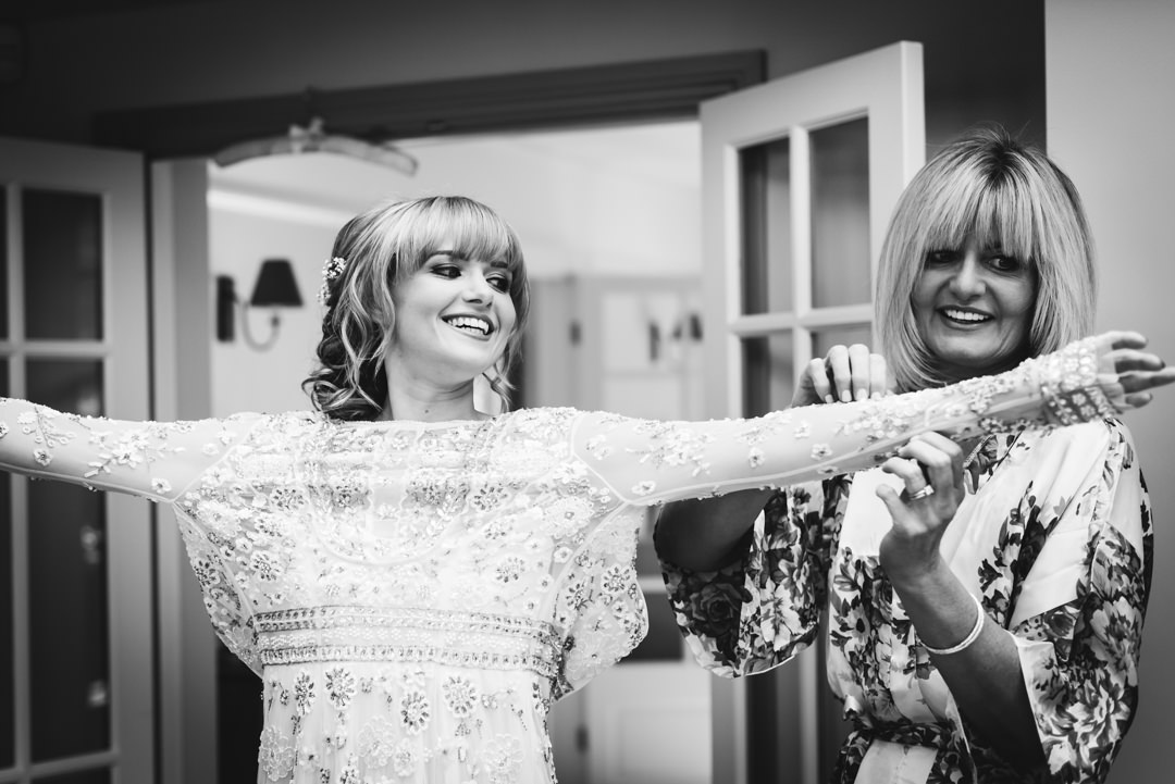 bride getting into her wedding dress with the help of her mum