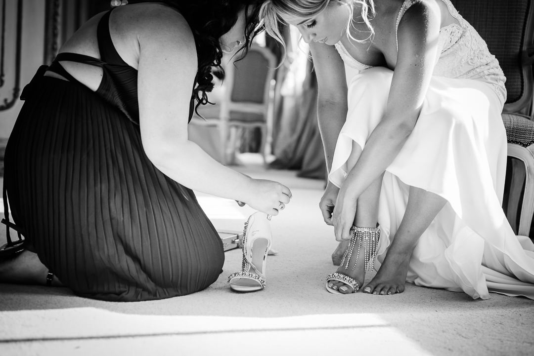 Chief bridesmaid help bride into her wedding shoes 