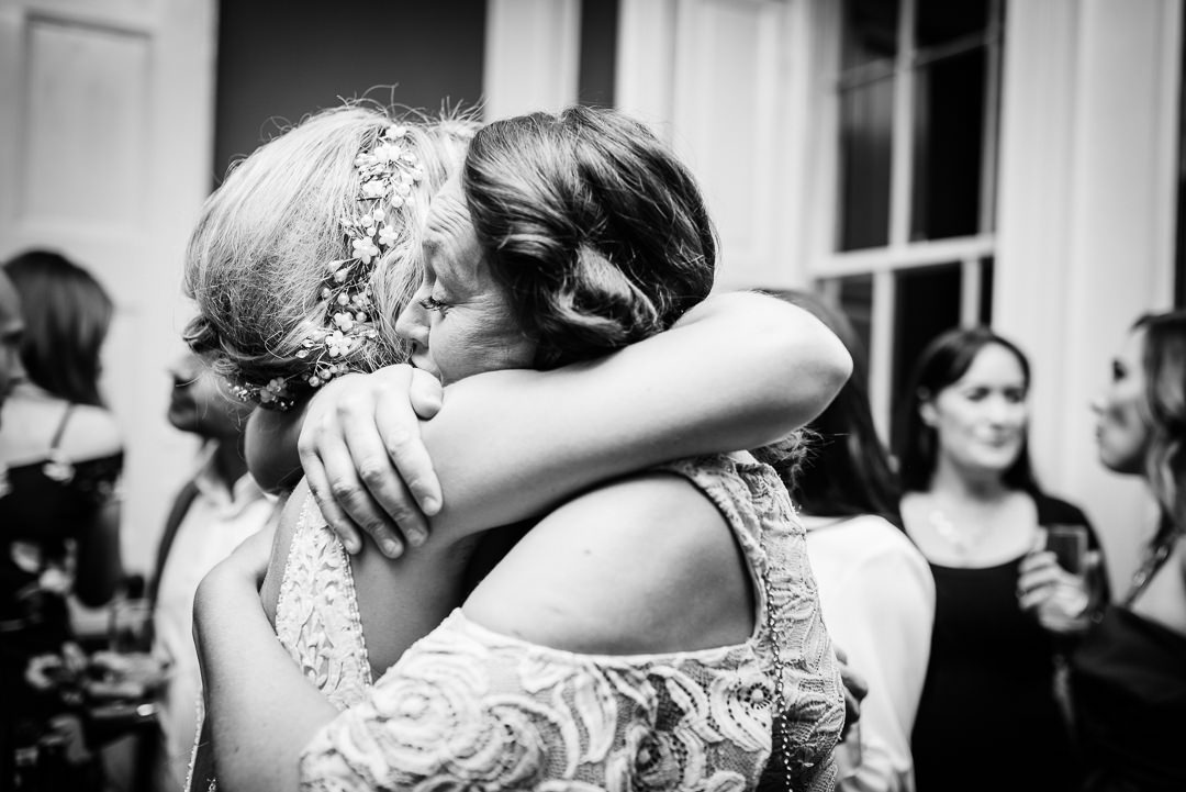Wedding guests hug in front of Hertfordshire wedding photographer