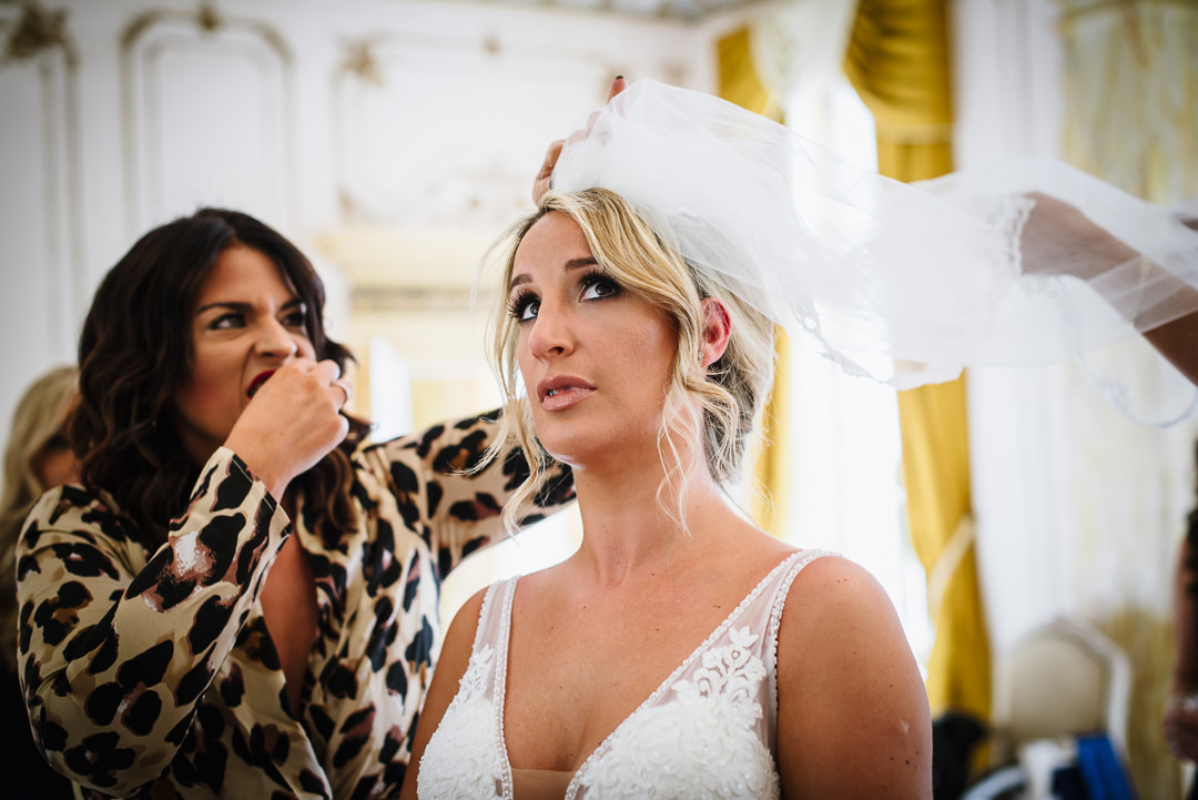 Bridal party help with last minute veil adjustments at Gosfiled Hall wedding in Essex