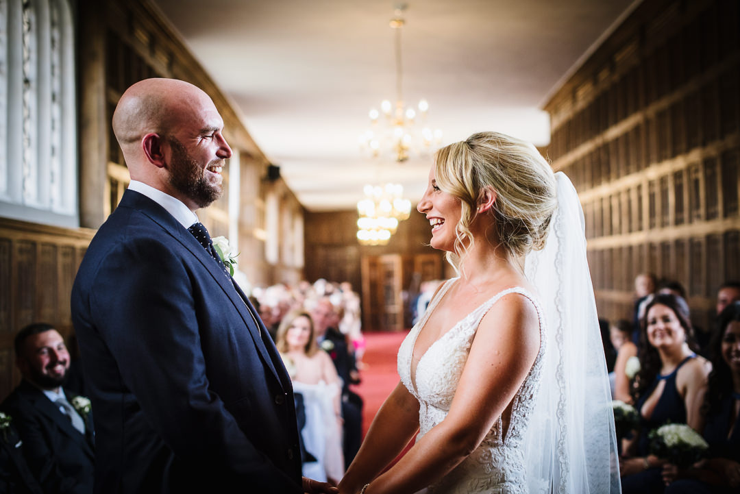 bridal and groom laugh as they exchange their wedding vows at Gosfiled Hall wedding