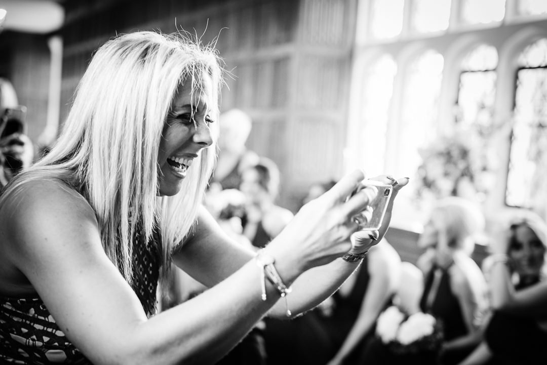 guest laughs as she takes a photo of the newly married couple Hertfordshire wedding photographer