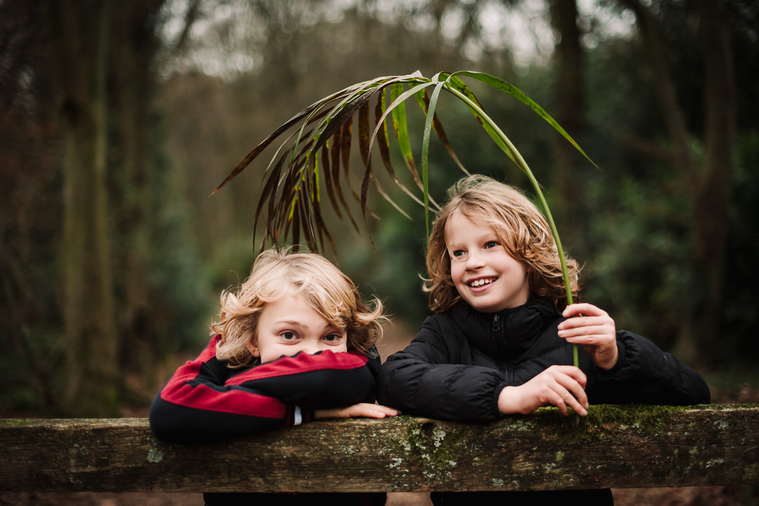two boys play with a leaf during their woodland photo shoot