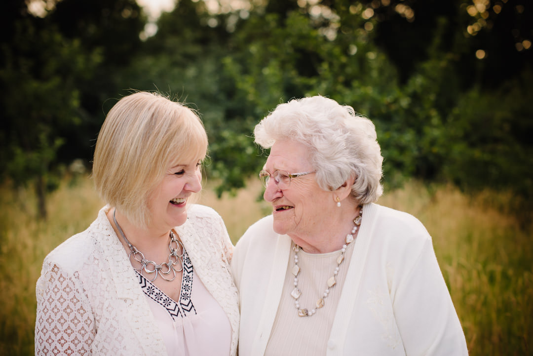 An elderly mother and her daughter giggle during their relaxed family photography St Albans.