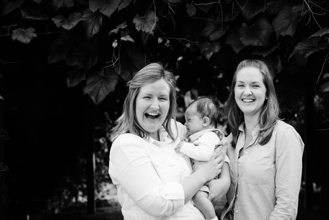 Two sisters laugh as they pose for relaxed family photography St Albans because the new baby cries!