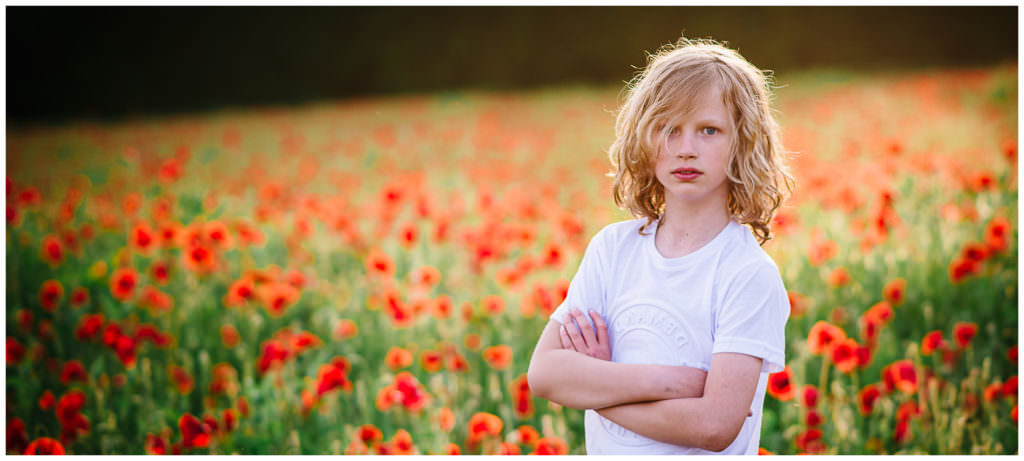 smiling boy in a poppy field at golden hour