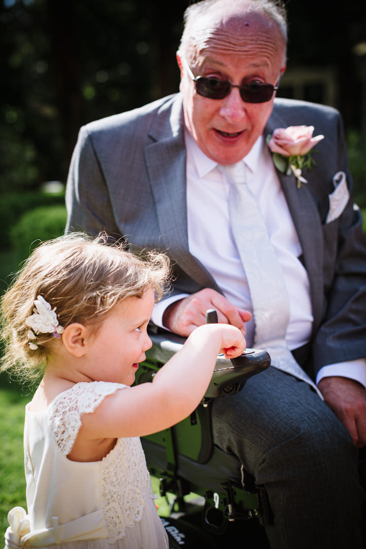 little bridesmaid plays with her granddads wheelchair at wedding reception