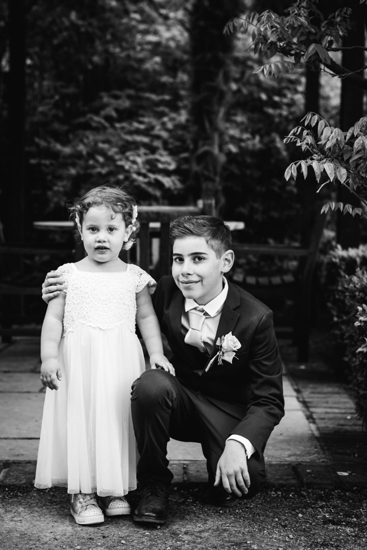 son and daughter of the bride and groom pose in the gardens of the bull hotel gerrards cross