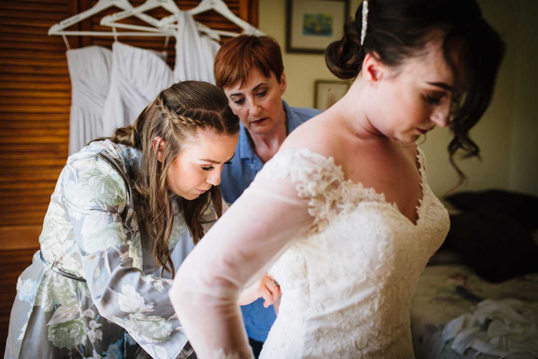 mother of the bride helps get bride into her wedding dress in hertfordshire