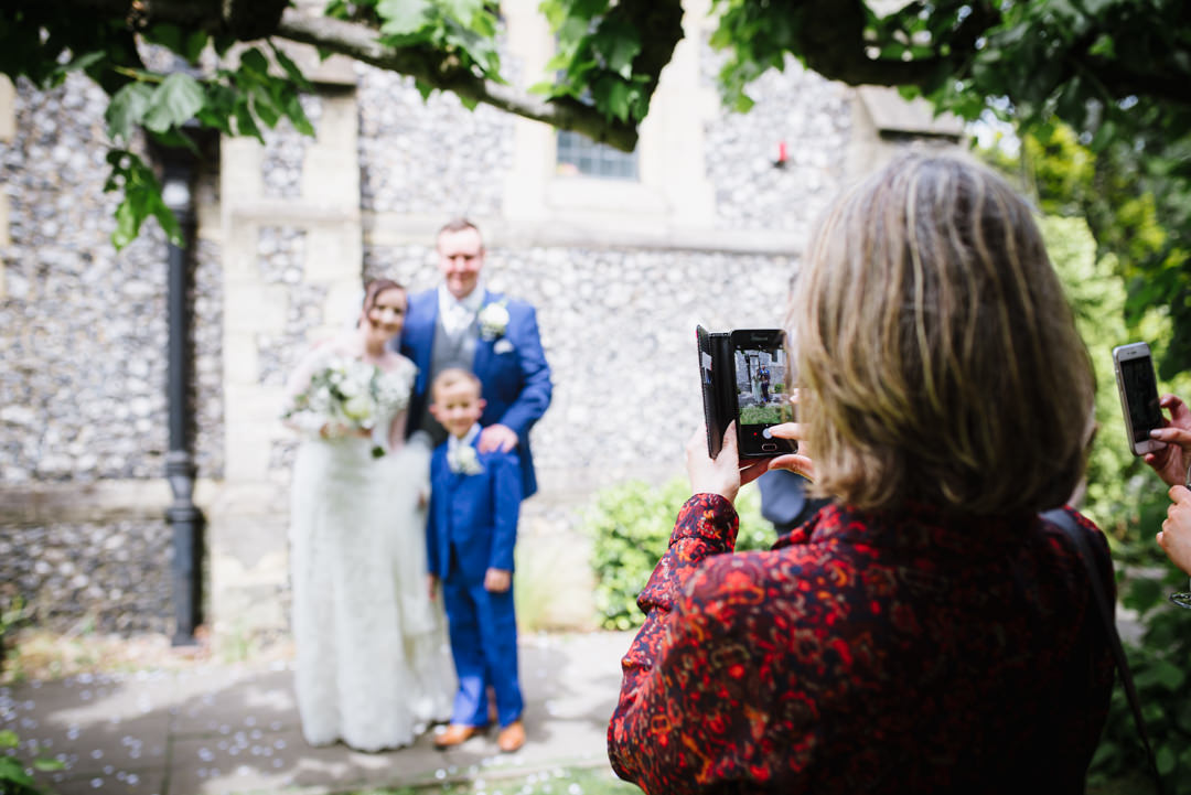 guest taking a photo of happy couple outside the church