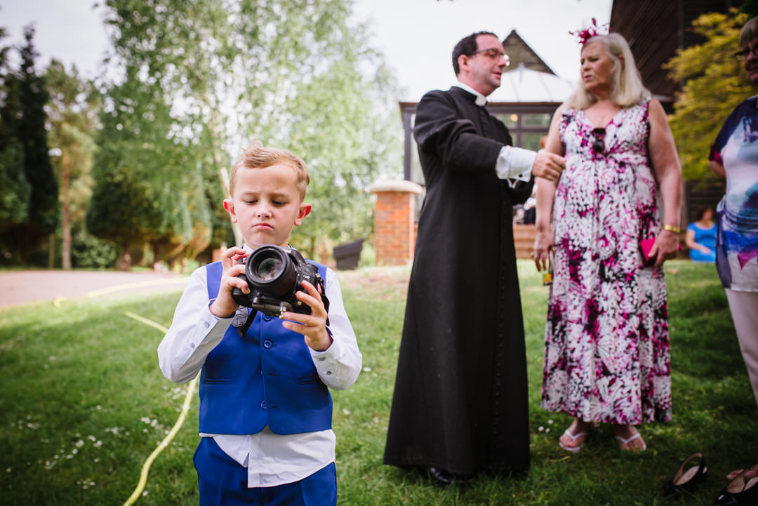 grooms son borrows wedding photographers camera to take a picture