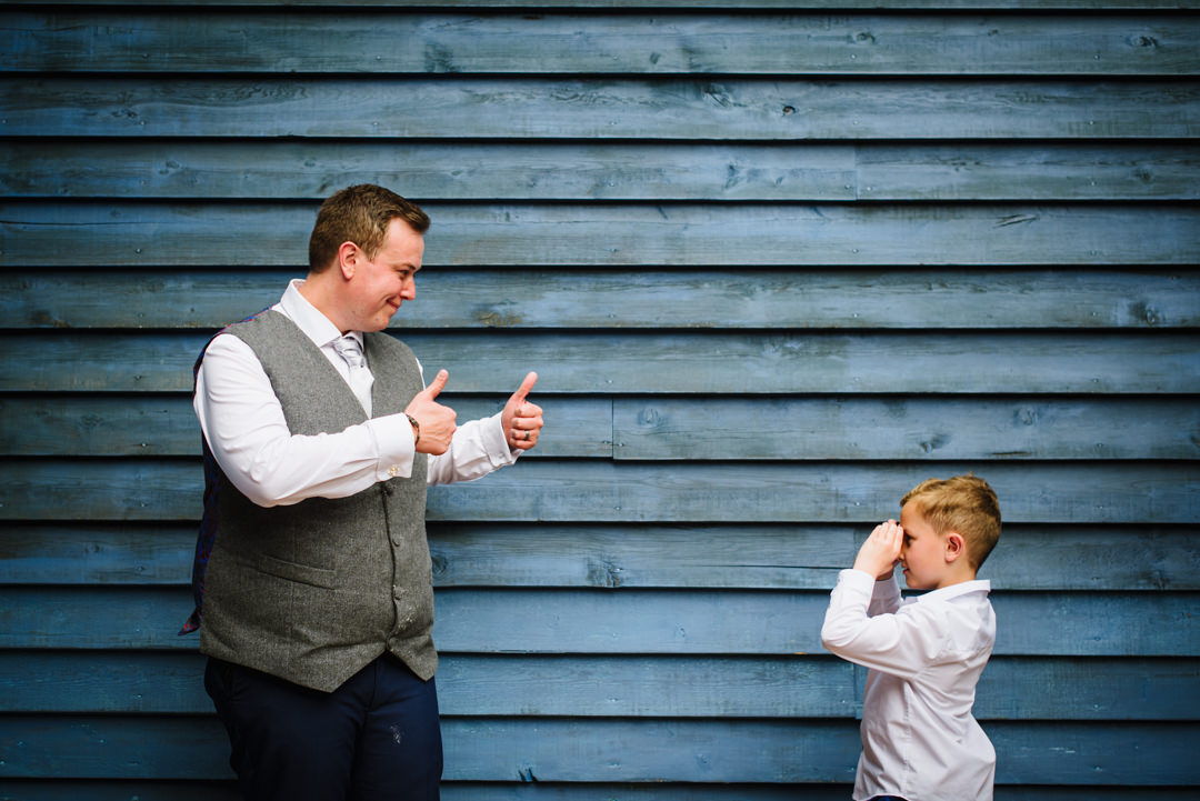 grooms son takes a photo of the groom against a blue wall at essendon country club