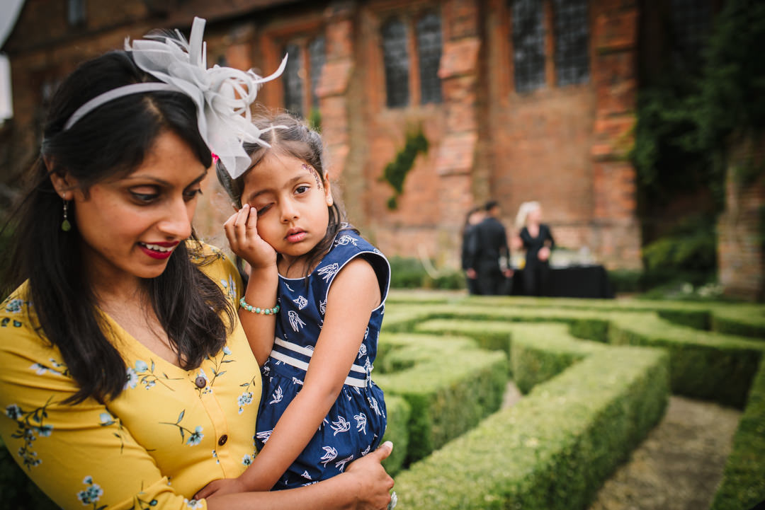 young wedding guest looks bored in the maze at hatfield house