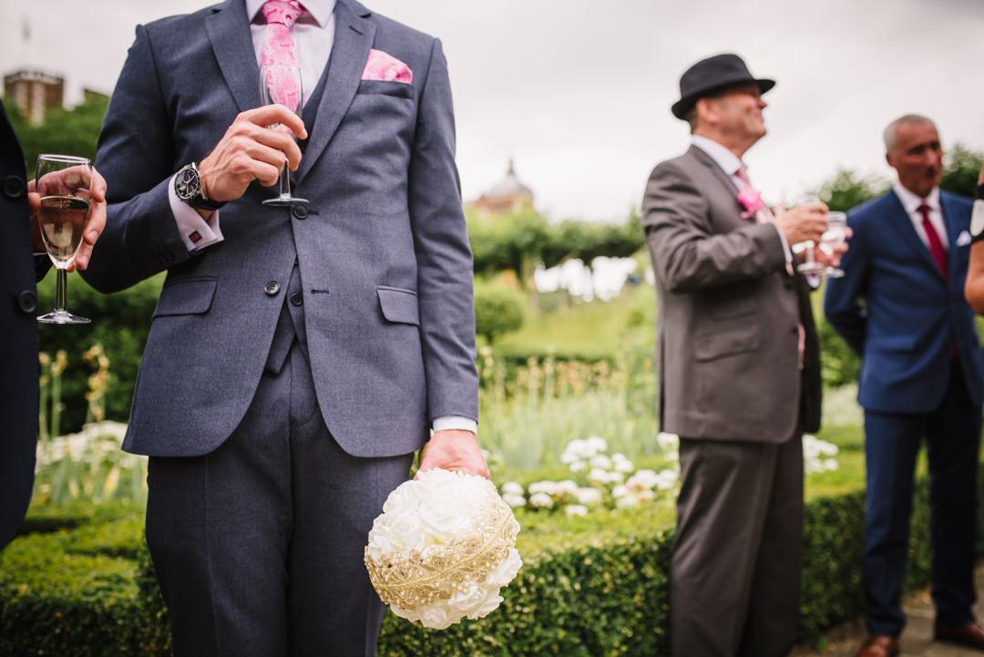 man holds the bouquet for the bride as well as his drink