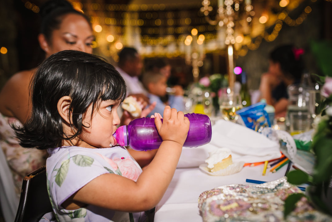 a very thirsty young wedding guest drinks from her bottle