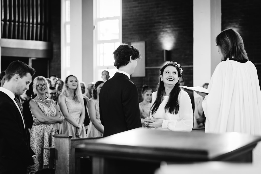 bride looks thrilled as she takes her wedding vows in st francis church welwyn garden city