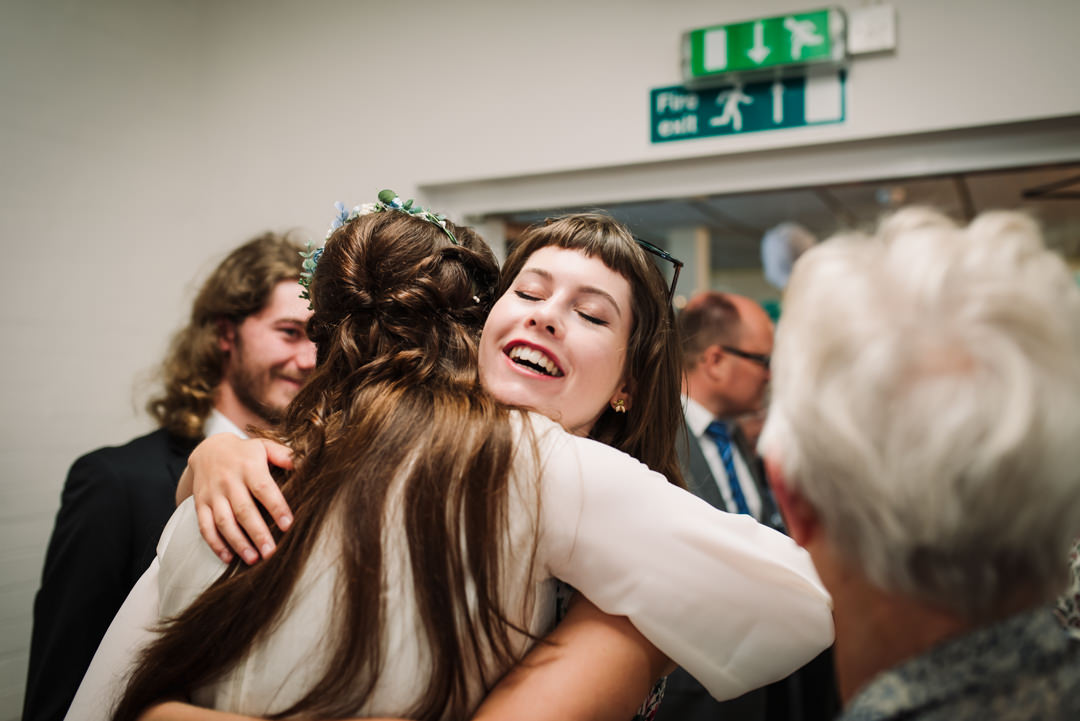friends hug the bride as they arrive at the welwyn garden city wedding