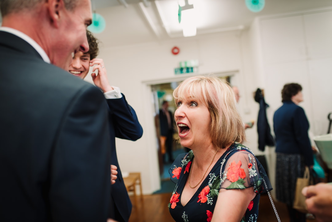 guest pulls an animated face whilst chatting to father of the groom