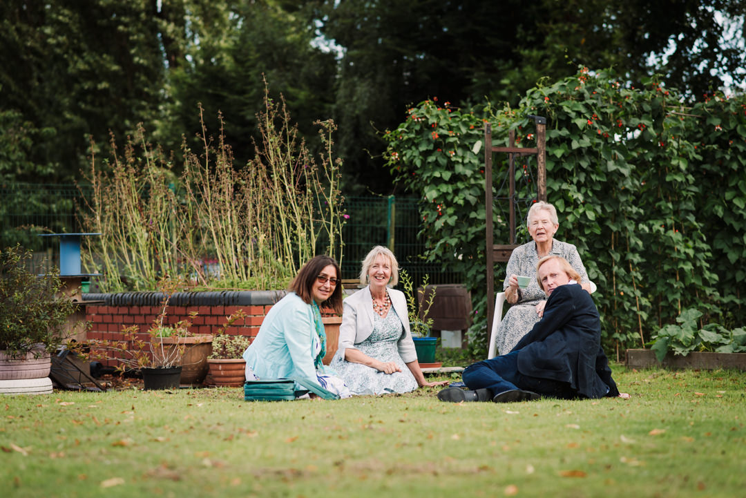 happy guests sit and chat amongst the veg patch in welwyn garden city wedding garden reception