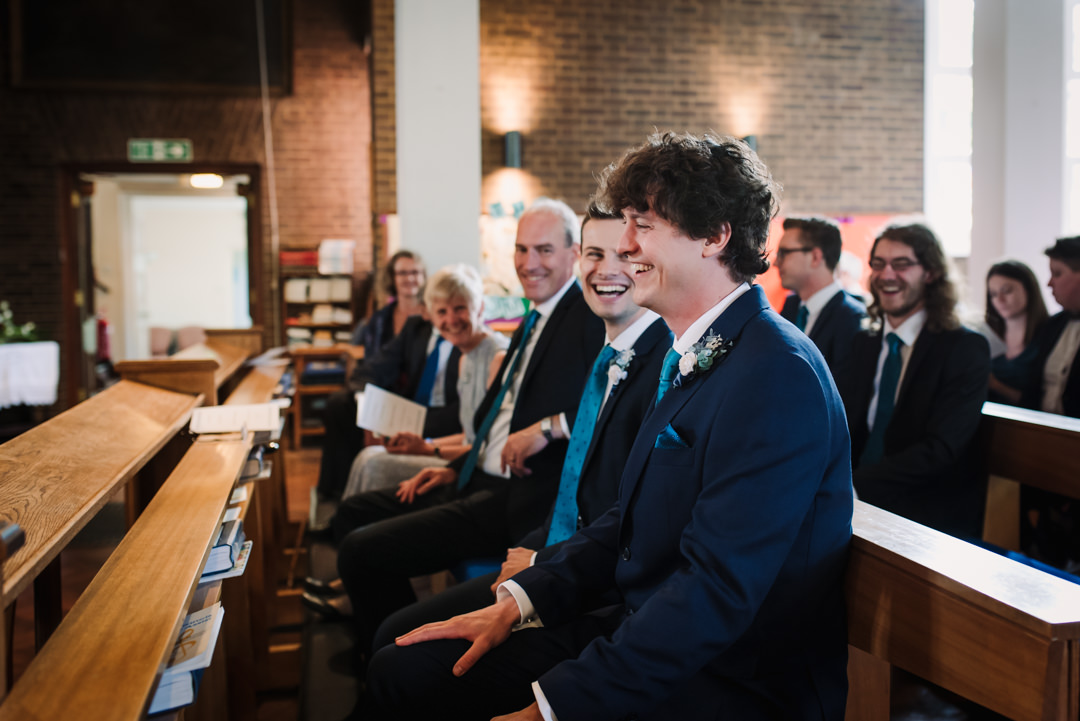 best man and groom laugh together as they wait for the welwyn garden city bride