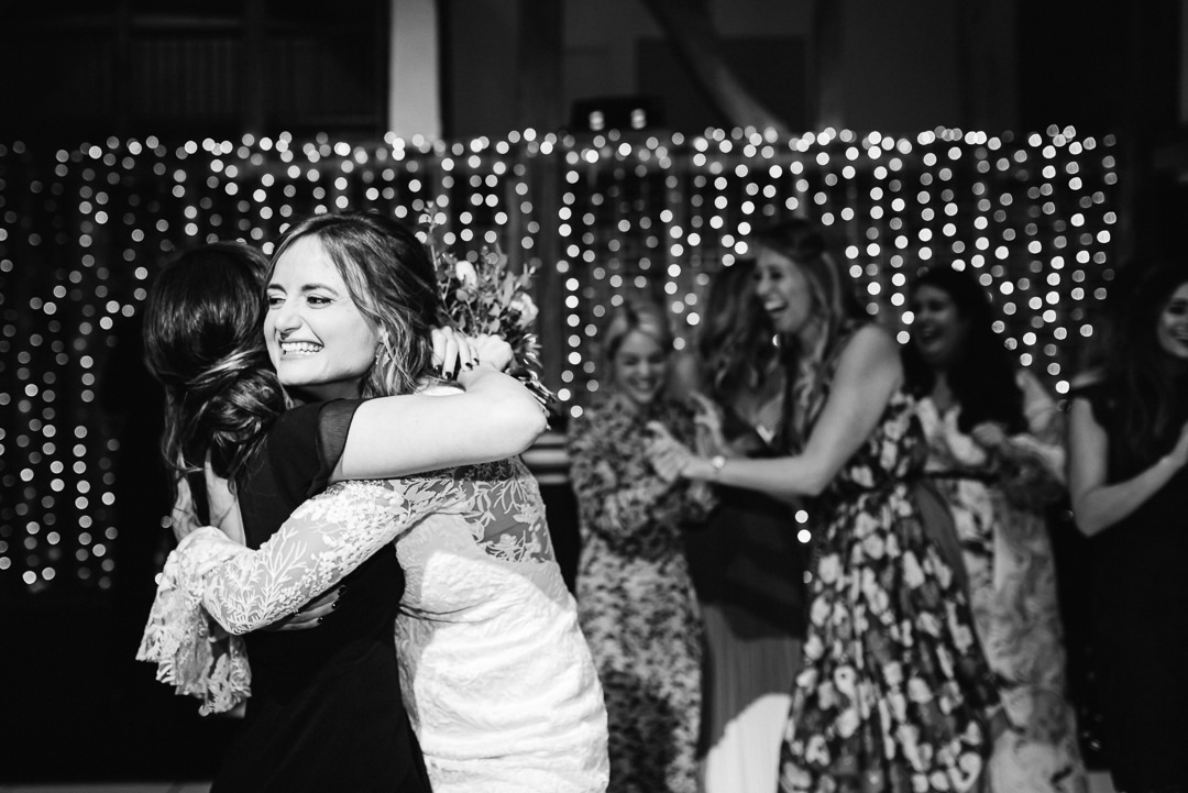 bride hugs her bridesmaid at her evening wedding reception