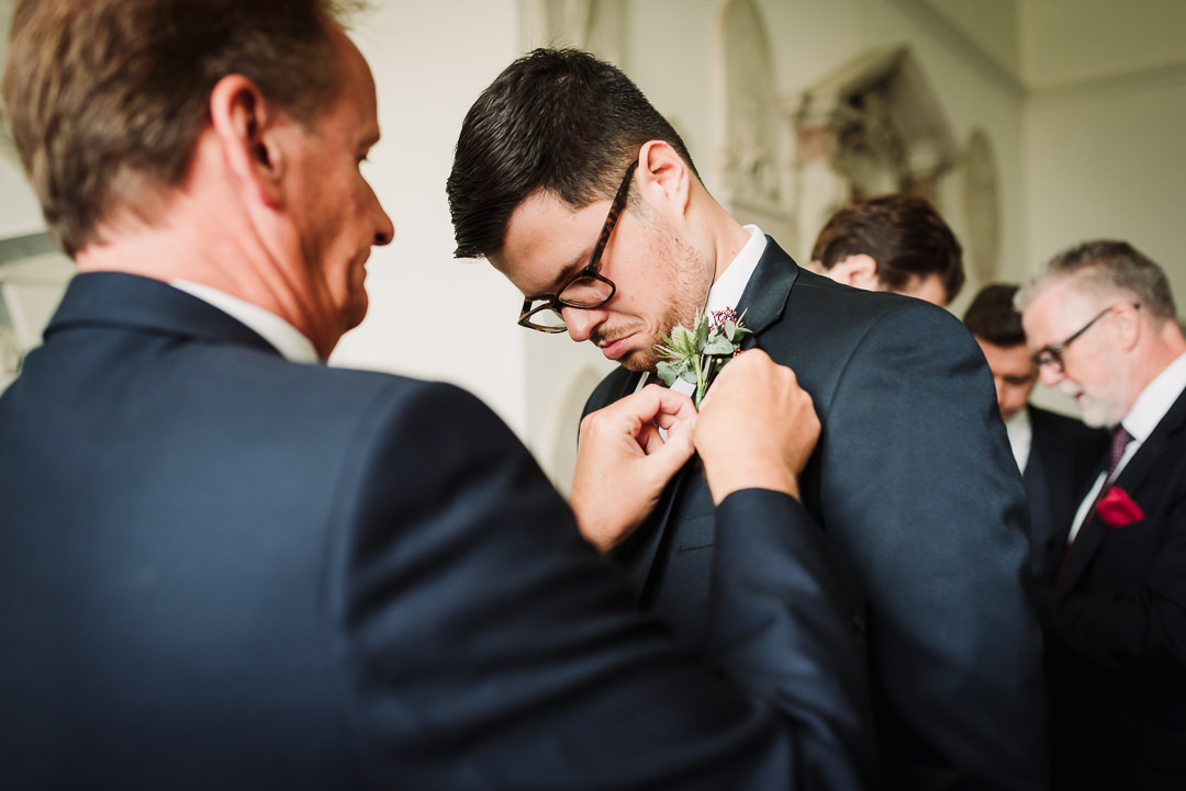 father of the bride helps best man pin his button hole before the micklefiled hall wedding