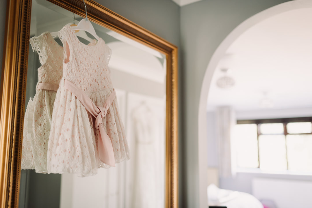 baby bridesmaids dress hangs on a mirror ready to put on