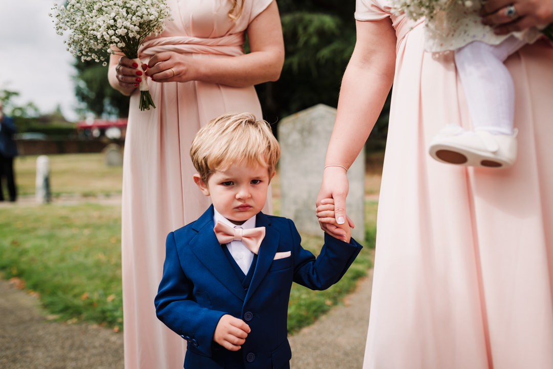 harpenden wedding photographer captures a nervous page boy holding his mums hand