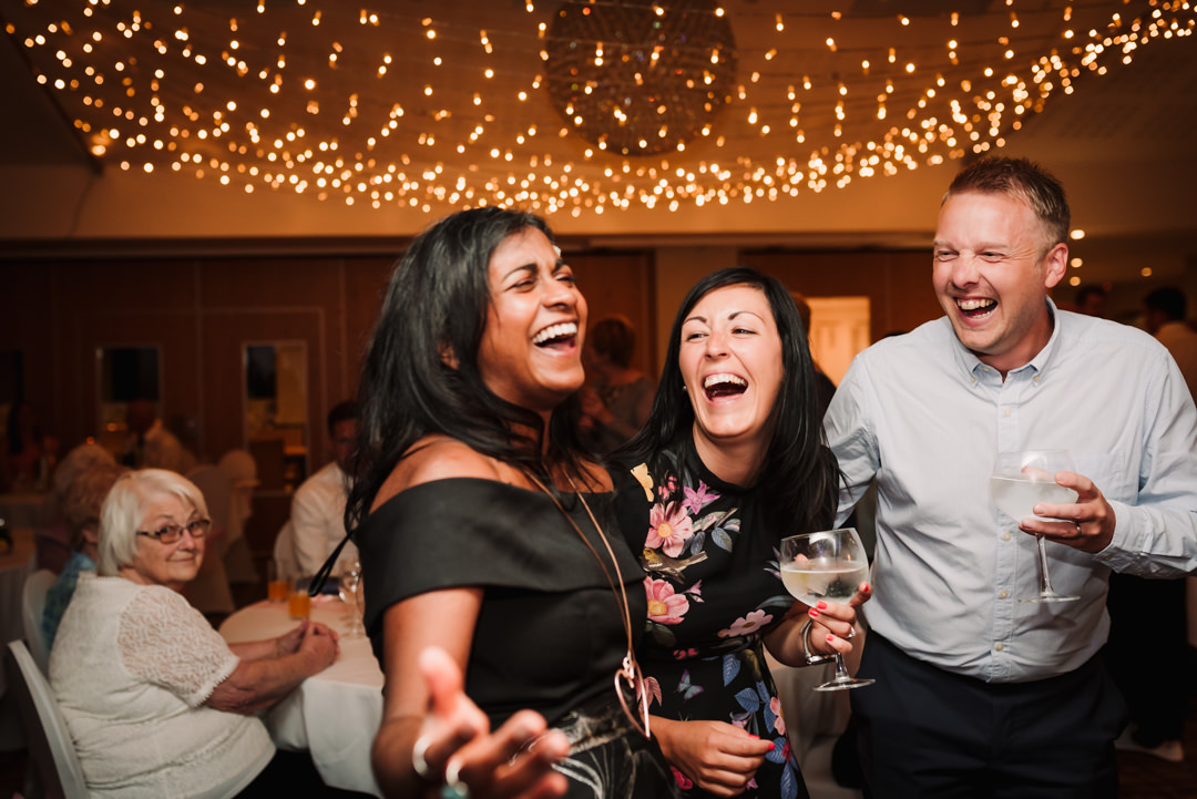 laughing merry wedding guests pose for harpenden wedding photographer