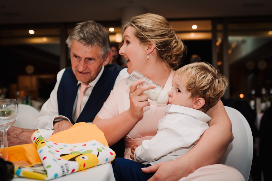 mum gives her son a quick milk bottle during the wedding party